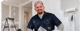 Painter smiling next to a ladder and paint roller